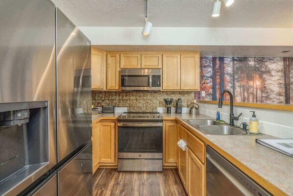 Una cocina moderna con electrodomésticos de acero inoxidable, armarios de madera y salpicadero de piedra.
