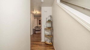 A narrow hallway with wooden flooring and a metal shelf unit against the wall.