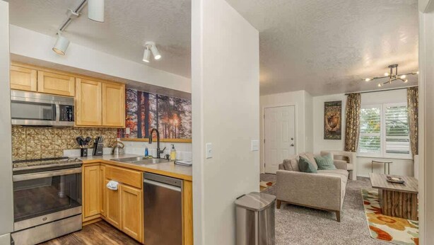 A modern kitchen with wooden cabinets, stainless steel appliances, and a tiled backsplash.