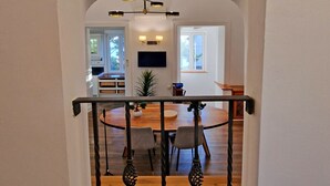A staircase with a wooden finish and black metal railings, leading to a dining area with a round table and chairs. - Private driveway + pool + views of the straits (Gibraltar)