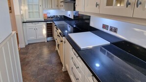 A kitchen with white cabinets, a black countertop, and a tiled floor. - Private driveway + pool + views of the straits (Gibraltar)