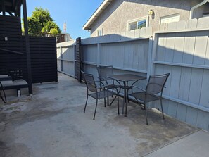 Eine Terrasse mit Tisch und Stühlen, ein Holzzaun und ein Gebäude im Hintergrund.