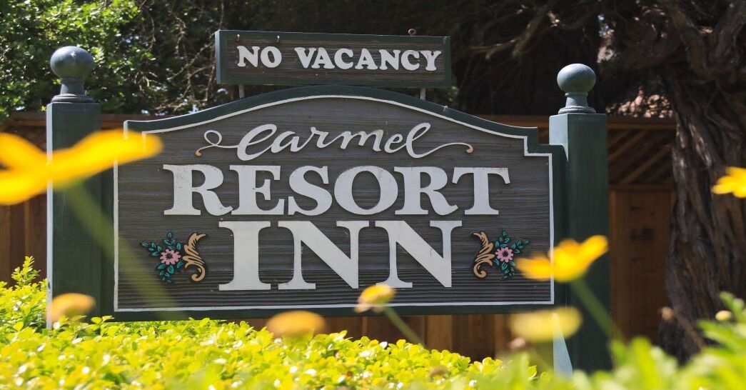 Naamplaatje voor Carmel Resort Inn met een 'Geen Kamers Beschikbaar'-bordje.
