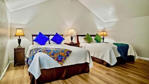 A bedroom with two beds, each with a white bedspread and a colorful blanket. There are two bedside tables with lamps, and the room has wooden flooring. - Luxury Carmel Suite  Walk 25 min walk  Carmel Beach 109 (Carmel)
