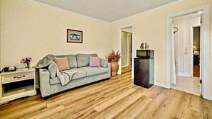A living room with a sofa, a coffee table, a side table, a potted plant, and a microwave. - Luxury Carmel Suite  Walk 25 min walk  Carmel Beach 109 (Carmel)