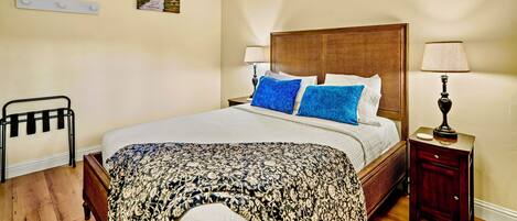 A neatly arranged bedroom with a wooden bed, a bedside table, a lamp, and a chair.