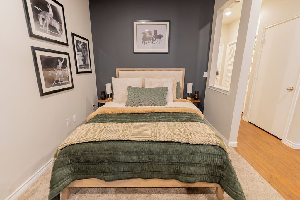 Une chambre à coucher avec un lit, des tableaux encadrés accrochés au mur et une porte sur le côté droit.