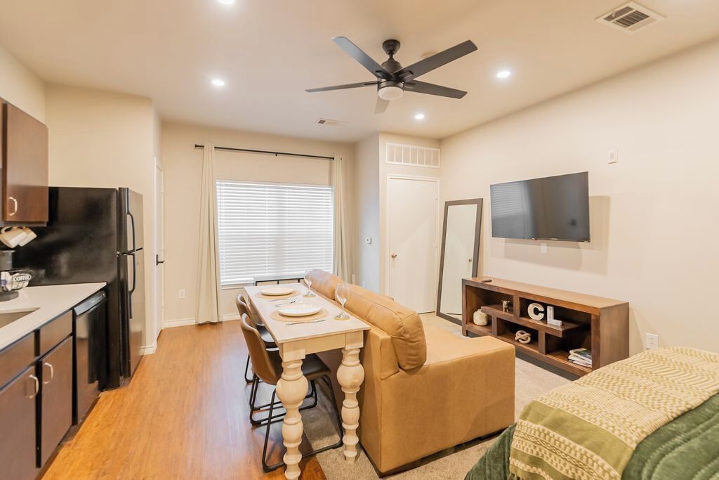 A compact living space with a kitchenette, dining area, and a TV mounted on the wall.