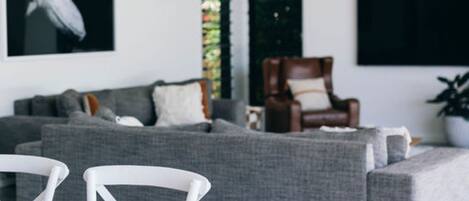 A living room with a grey sofa, a wooden dining table, and a brown armchair.