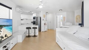 Une chambre d’hôtel moderne dotée d’un grand lit, d’une télévision, d’une kitchenette et offrant une vue sur la plage.