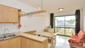 A compact kitchen with wooden cabinets, a sink, and a dining area with a table and chairs. - Cosy apartment for 5 guests with A/C, WIFI, TV, balcony and pets allowed (San Michele Al Tagliamento)