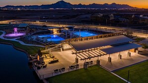 An aerial view of a resort with multiple swimming pools, a covered area with seating, and a view of distant mountains. - 3-bedroom Home in beautiful Queen Creek! (Queen Creek)