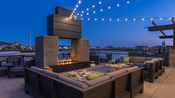 An outdoor patio with a built-in fire feature, seating, and string lights. - 3-bedroom Home in beautiful Queen Creek! (Queen Creek)