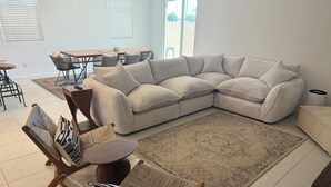 A living room with a sectional sofa, a dining table, chairs, and a patterned rug. - 3-bedroom Home in beautiful Queen Creek! (Queen Creek)