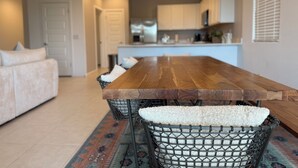 A modern kitchen with white cabinets, a wooden dining table, and a patterned rug. - 3-bedroom Home in beautiful Queen Creek! (Queen Creek)
