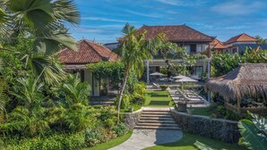 Un complexe hôtelier tropical doté d’une piscine centrale, d’une végétation luxuriante et d’une architecture traditionnelle.
