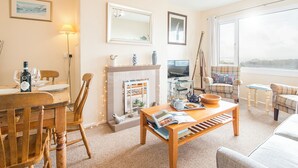 A cozy living room with a fireplace, a television, and a view of the outdoors. - Ty Peggie, Holiday cottage Solva, Sleeps 4, 2 bedrooms,  bathrooms (Haverfordwest)