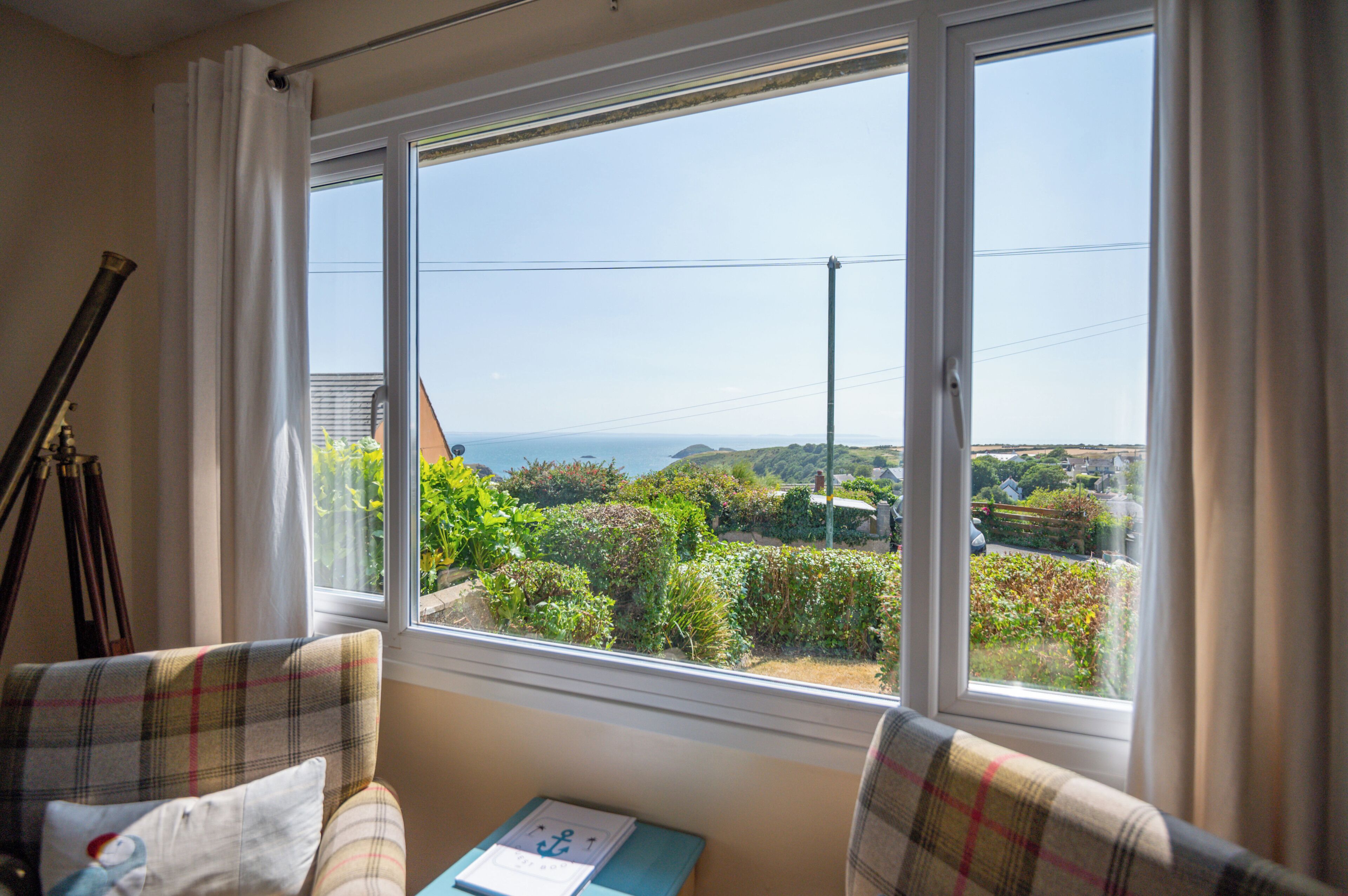 A room with a large window offering a view of a garden and distant landscape.