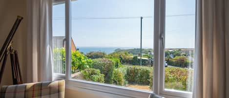 A room with a large window offering a view of a garden and distant landscape.
