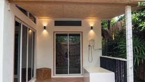 A covered outdoor area with a shower, a wooden stool, and a tiled floor. - Bamboo house (Tambon Choeng Thale)