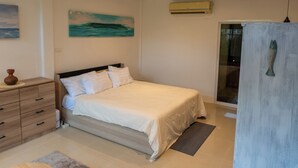 A bedroom with a bed, a dresser, a painting, an air conditioning unit, and a door. - Bamboo house (Tambon Choeng Thale)