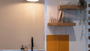A kitchen with a wooden cabinet, a countertop, and a hanging light fixture. - Bamboo house (Tambon Choeng Thale)