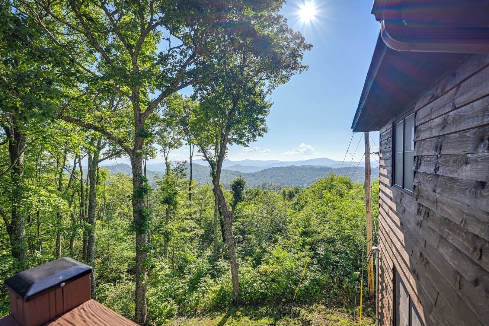 Une cabane en bois offrant une vue sur une forêt et des montagnes lointaines.