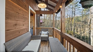 Una terraza de madera con mobiliario de mimbre y un colgador de luces.