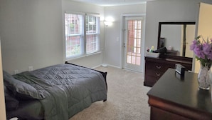 A bedroom with a bed, dresser, and a door leading to an outdoor area. - 2-bed apartment, heart of RIO, Gaithersburg! Near 1-270, commuter convenient. (Gaithersburg)
