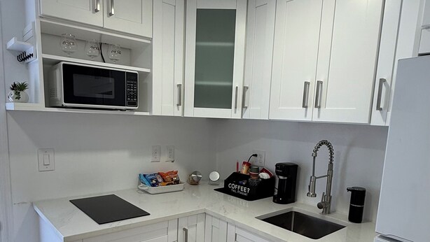 A compact kitchen with white cabinets, a microwave, a coffee maker, and a sink. - Perfect terrace to relax, have a coffee or enjoy the Florida weather. (Tampa)