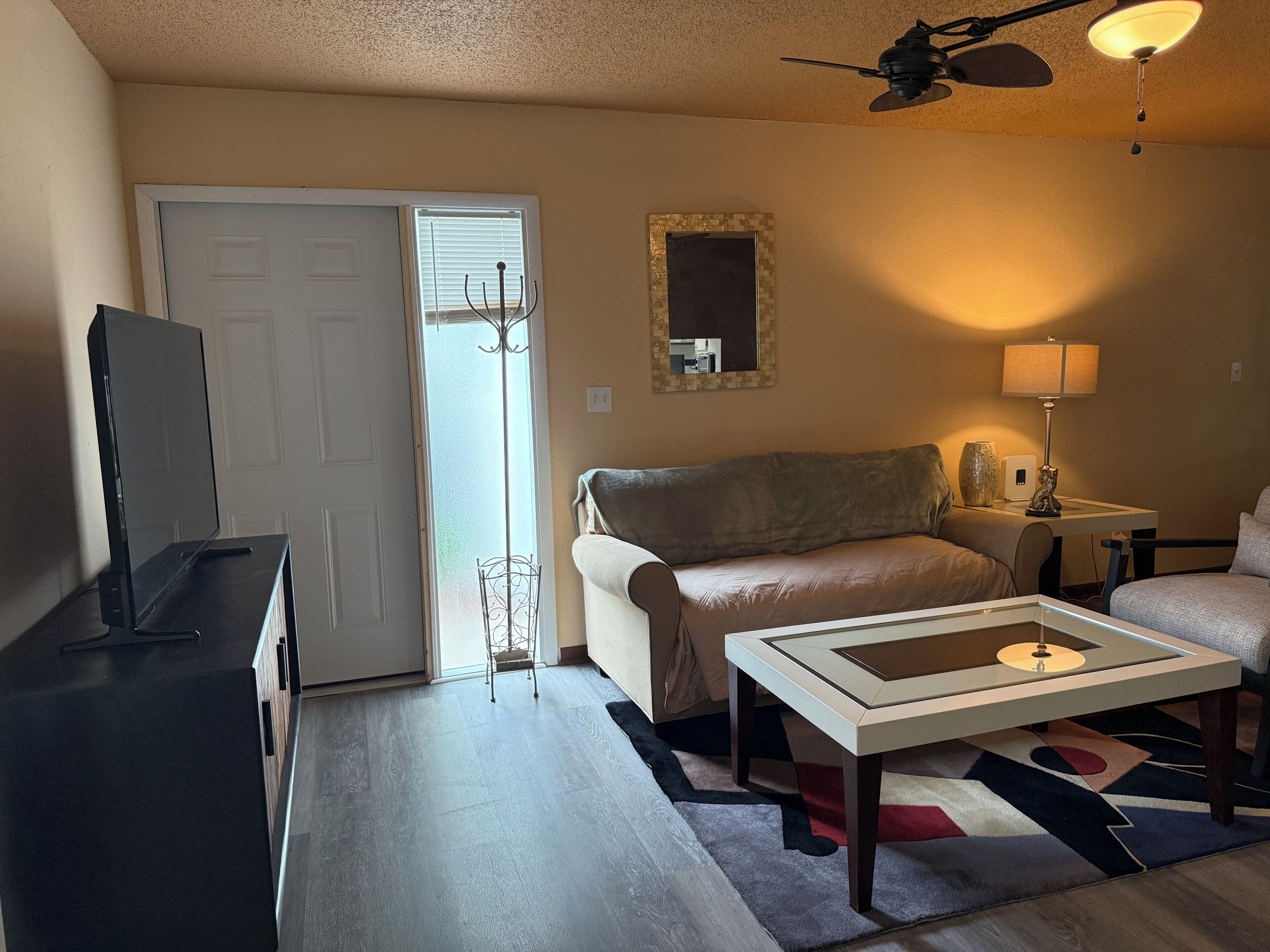 Un salon comprenant un canapé, une table basse, un téléviseur, un ventilateur de plafond et une lampe.