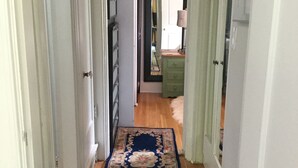 Un corridoio con una moquette a motivi floreali blu, parquet in legno e pareti bianche.