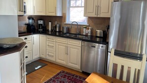 Cucina con mobili chiari, frigorifero in acciaio inossidabile, lavastoviglie e macchina da caffè.