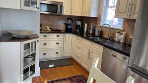 Una cucina moderna con mobili bianchi, elettrodomestici in acciaio inossidabile e pavimento in legno.