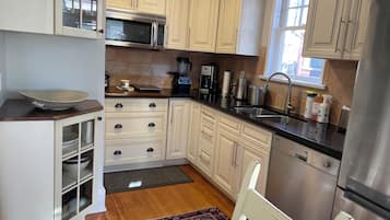 A modern kitchen with white cabinetry, stainless steel appliances, and a wooden floor.