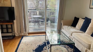 A living room with a glass coffee table, a sofa, and a TV.