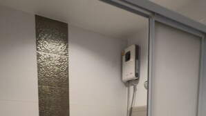 Casa de banho moderna com cabine de duche em vidro, sanita branca e um tabouretinho branco.