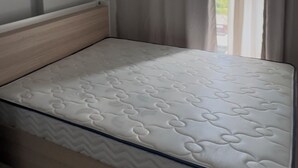 Quarto com uma cama de solteiro, janela com cortinas e uma luminária no teto.