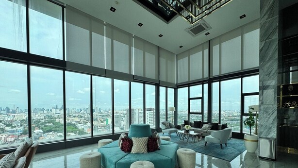 Uma sala de estar ampla com vista para a cidade, grandes janelas e móveis modernos.