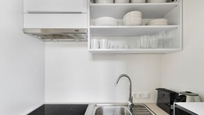 A modern kitchen with a stainless steel sink, a built-in stove, and white cabinetry. - Blueground | Wieden, view, nr Belvedere (Vienna)
