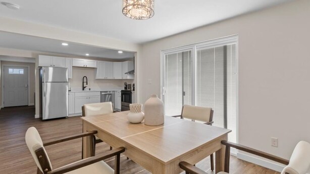A modern kitchen with white cabinets, a stainless steel refrigerator, and a pendant light.
