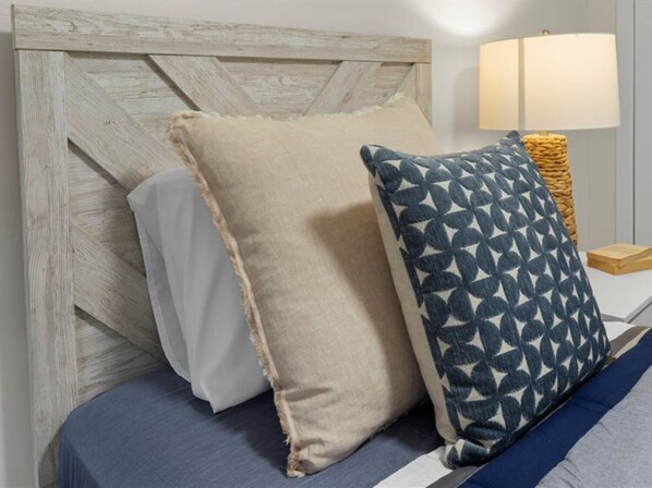 Una cama con dos almohadas, cabecera de madera y una lámpara de noche.