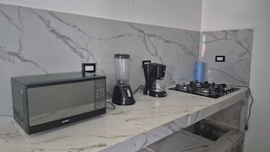Une cuisine équipée d’un four à micro-ondes, d’un mixeur et d’une cuisinière à gaz.