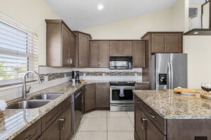 Eine moderne Küche mit Granit Arbeitsplatten, Edelstahlgeräten und dunklen Holzschränken.
