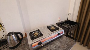 Une petite cuisine équipée d’une cuisinière à gaz, d’une bouilloire et d’un évier.