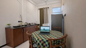 Une petite cuisine équipée d’une cuisinière, d’une bouilloire et d’un ordinateur portable posé sur une table.