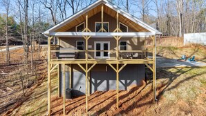A two-story house with a balcony, a covered deck, and a visible air conditioning unit. - True Love Cabin — A Romantic Escape Above the Pines (Cleveland)