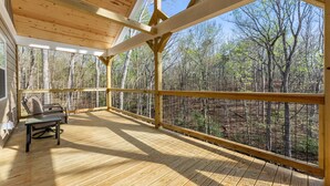 A wooden deck with a view of a forest, a chair, and a table. - True Love Cabin — A Romantic Escape Above the Pines (Cleveland)
