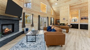 Ein Blockhaus-Interieur mit Kamin, Sofa, Couchtisch und Billardtisch.