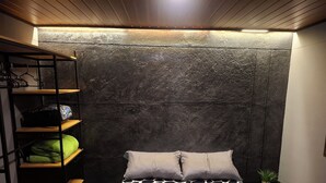 A bedroom with a bed, a shelf unit, and a wall with a textured finish. - Loft authentic coffee axis (Risaralda)